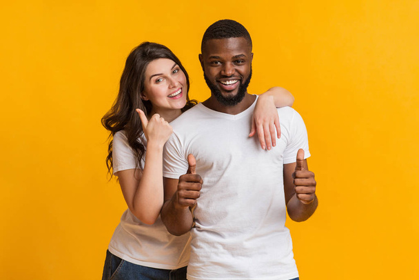 Happy millennial couple embracing and gesturing thumbs up at camera - Photo, Image