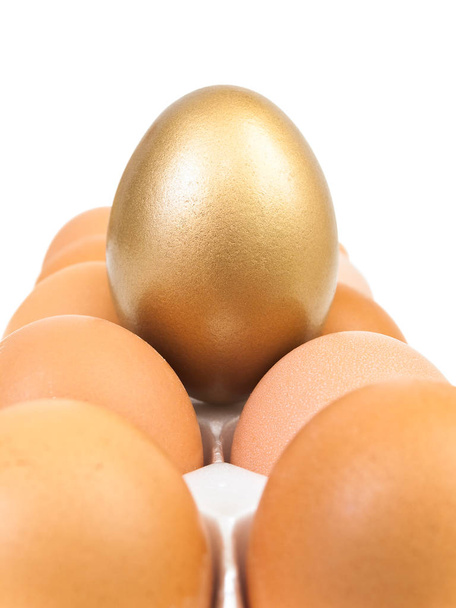 gouden ei bij de gebruikelijke eieren tegen de witte achtergrond - Foto, afbeelding