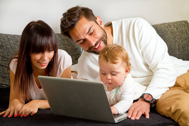 happy family with a laptop and a young girl on the floor - Foto, imagen