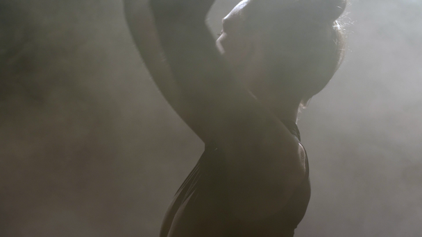 Silhouette of female dancing among puffs of smoke - Felvétel, videó