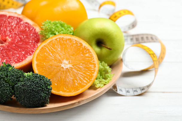 Fruits, vegetables and measuring tape on white wooden background, closeup. Visiting nutritionist - Fotografie, Obrázek