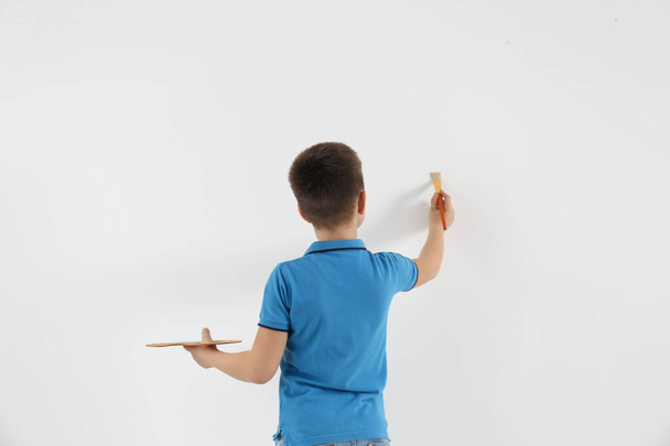 Little child painting on white wall indoors - Foto, Imagem