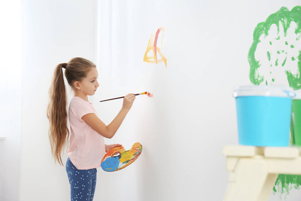 Little child painting on white wall indoors - Fotó, kép