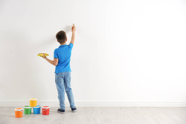 Little child painting on white wall indoors. Space for text - Foto, Imagem