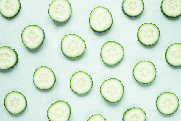 Pattern with freshly cut cucumber slices on green background - Photo, Image