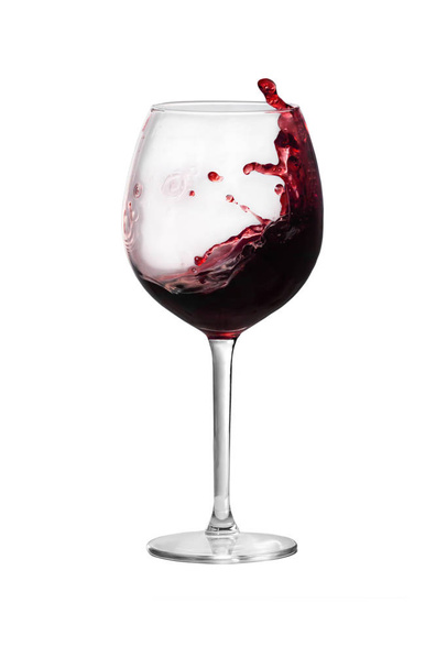Red wine is splashing out of a wine glass - Φωτογραφία, εικόνα