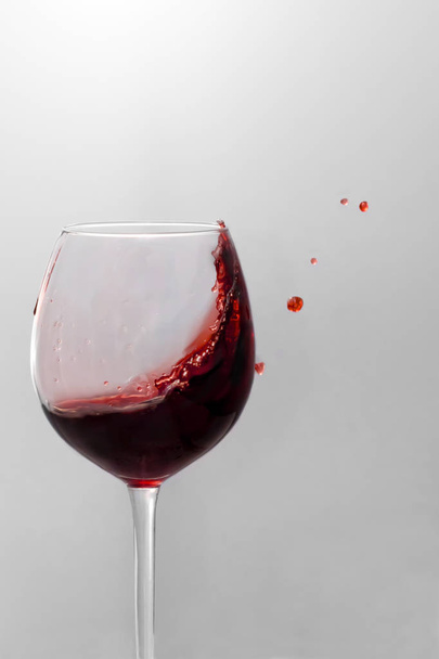 Red wine is splashing out of a wine glass - 写真・画像