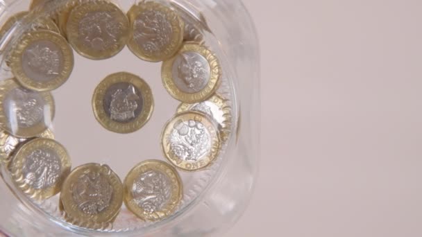 Μια κοντινή οπτική του σκουληκιού κάποιου ρίχνει μερικά κέρματα λίβρα σε ένα γυάλινο βάζο σε αργή κίνηση - Πλάνα, βίντεο