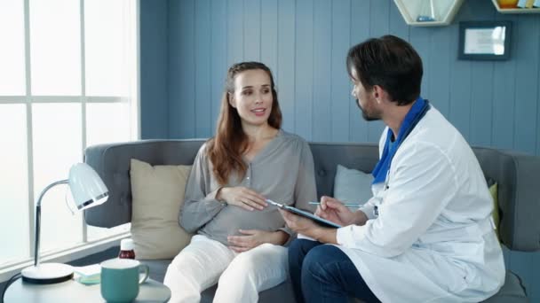 Hymyilevä raskaana oleva nainen puhuu lääkärin kanssa synnytysklinikalla
. - Materiaali, video