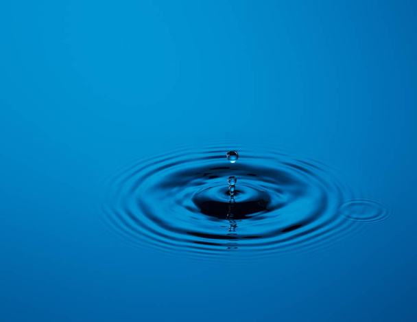 water drop falling into the clear blue background - Fotoğraf, Görsel