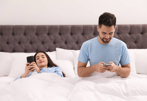 Young couple addicted to smartphones in bed at home - Foto, Imagem