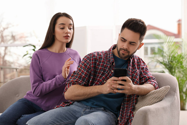 Distrustful young woman peering into boyfriend's smartphone at h - Foto, Imagem