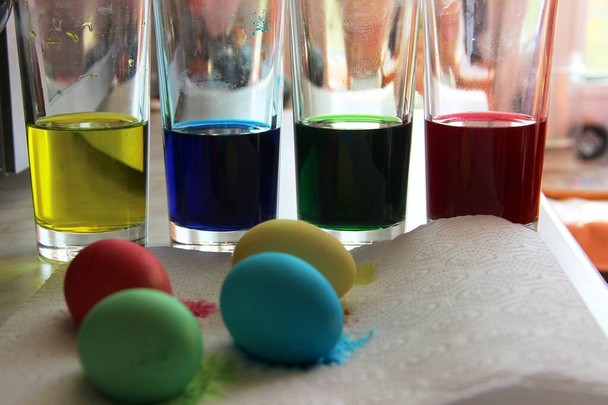 quatre verres d'affilée avec de la peinture jaune, bleue, verte et rouge, cuisson pour Pâques. peindre des œufs pour le lapin de Pâques
 - Photo, image