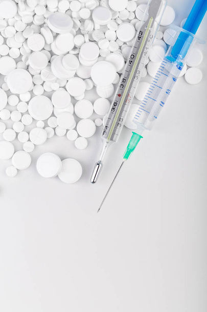 Bunch of white pills with green injection and thermometer - Foto, afbeelding