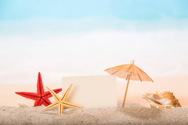 Blank card, starfish, umbrella and sea shell close-up in the san - Foto, imagen