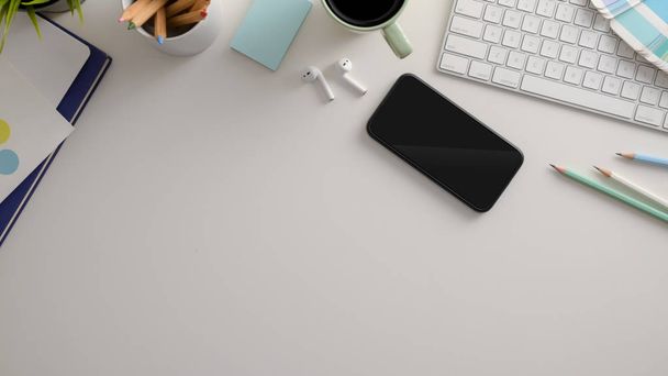 Ansicht des stilvollen Arbeitsplatzes mit Smartphone-Buntstiften, Computertastatur und anderen Büroutensilien  - Foto, Bild