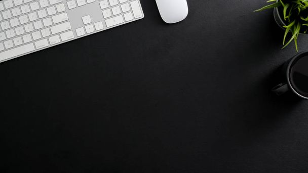 Overhead-Aufnahme eines dunklen modernen Arbeitsplatzes mit Computertastatur, Kaffeetasse und Kopierraum  - Foto, Bild