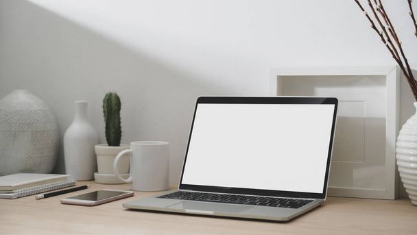 Schnappschuss eines modernen Arbeitsplatzes mit leerem Bildschirm Laptop, Smartphone, Bürobedarf und Dekorationen  - Foto, Bild