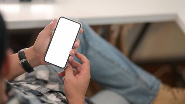 Joven hombre sosteniendo la pantalla en blanco smartphone con relajarse sentado
 - Foto, imagen