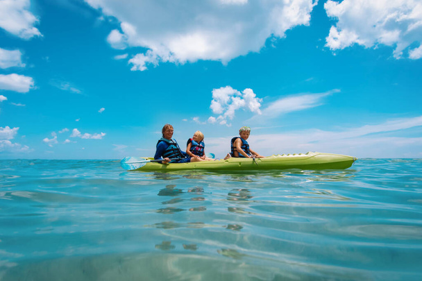 Отец с сыном и дочь на каяке на пляже каникулы
 - Фото, изображение