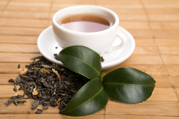 ένα φλιτζάνι πράσινο τσάι με τα αξιοθετα φύλλα - Φωτογραφία, εικόνα