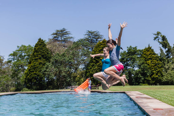 Girls running jumping into home  swimming pool summer playtime - Valokuva, kuva