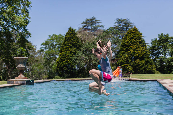 Girls running jumping into home  swimming pool summer playtime - Fotó, kép