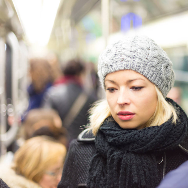 Beautiful blonde caucasian lady wearing winter coat traveling by metro in rush hour. Public transport. - Foto, Imagen