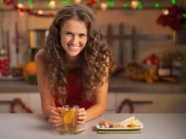 Smiling young woman drinking ginger tea in christmas decorated k - Photo, image