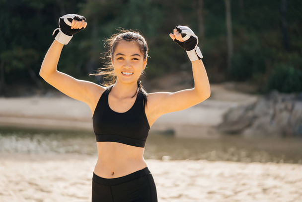 Portrét silné mladé asijské ženy sportovec protahování svaly v boxerských rukavicích a zažívá štěstí pocit vítězství. - Fotografie, Obrázek