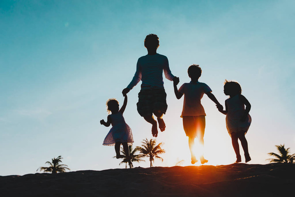 glücklicher Vater mit Kindern, die vor Freude bei Sonnenuntergang springen - Foto, Bild