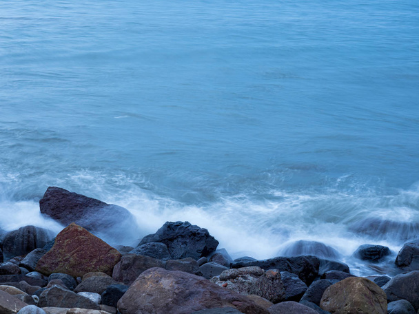 belle onde d'acqua liscia e setosa e rocce sulla riva del mare
 - Foto, immagini