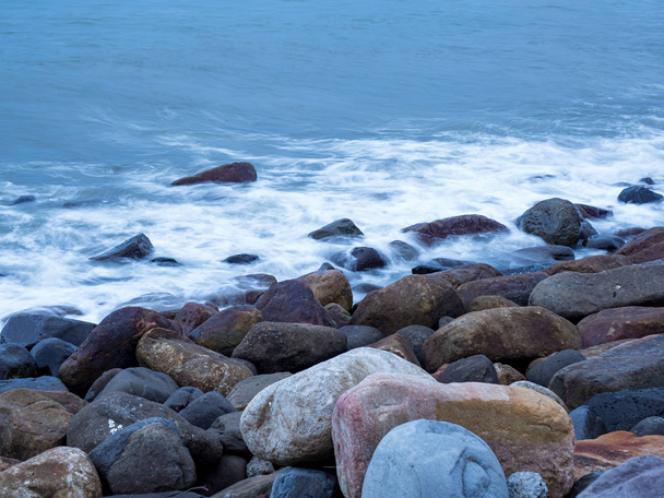 belle onde d'acqua liscia e setosa e rocce sulla riva del mare
 - Foto, immagini