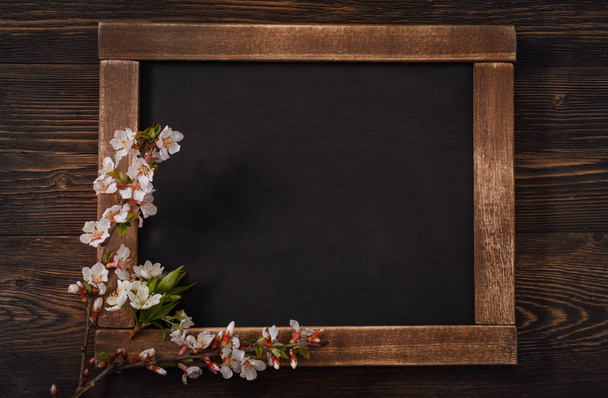 Old blank vintage school slate or chalkboard lying on an old rustic wooden background with dainty white flowers in two corners ready for your text or message - Fotoğraf, Görsel