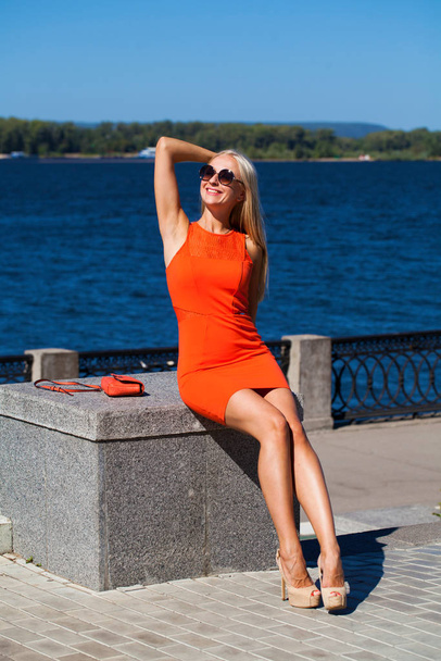 Young beautiful woman in orange dress on the summer street - Fotografie, Obrázek
