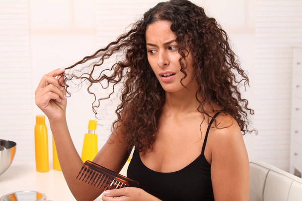 young woman combing her curly hair - Фото, зображення