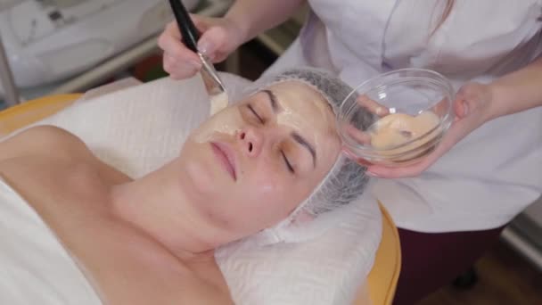 Profesjonalna kosmetolog kobieta zakłada maskę na twarz pacjenta. - Materiał filmowy, wideo
