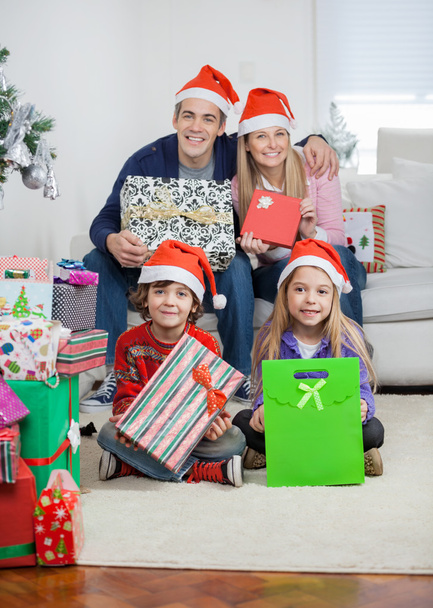 Family In Santa Hats Holding Christmas Gifts - Фото, зображення