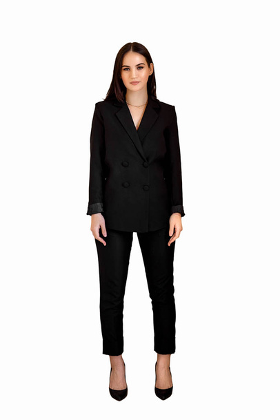 a young Caucasian businesswoman girl in a black Trouser suit stands tall on a white isolated background - Фото, зображення