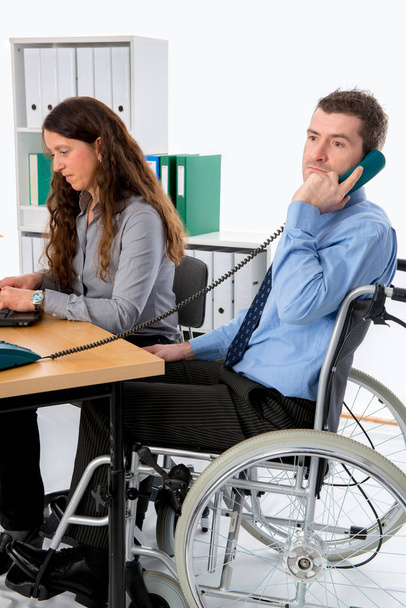 man in wheelchair and his  is female colleague working in the office - Foto, imagen