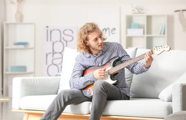 Mies soittaa kitaraa kotona - Valokuva, kuva