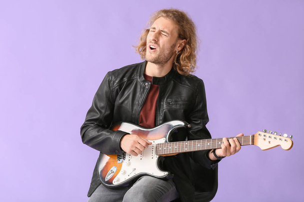 Mann spielt Gitarre und singt auf farbigem Hintergrund - Foto, Bild