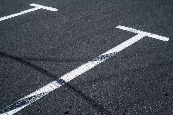 Asphalt surface of the empty parking with white road marking lines and wheel tracks - Valokuva, kuva