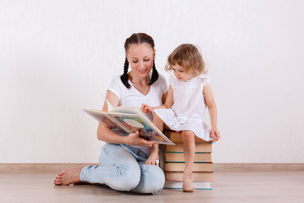 Genç anne ve küçük kızı odada kitapları okudu. Mutlu bir aile. Erken gelişim ve öğrenme. - Fotoğraf, Görsel