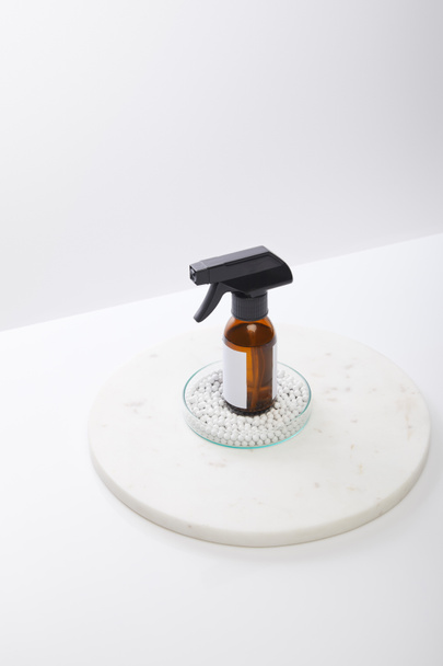 Hochwinkel-Ansicht der Spenderflasche mit kosmetischem Öl im Inneren von Laborgläsern mit dekorativen Perlen isoliert auf grau  - Foto, Bild