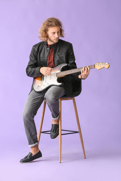 Man playing guitar on color background - Fotó, kép