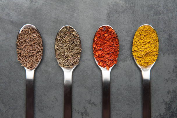 different spices on spoons lie on a slate plate. cumin,thyme,chili,curry - Foto, afbeelding