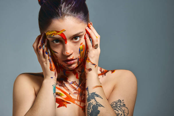 Portrait of a beautiful girl in the paint. Closeup portrait of a girl with face and hands with different paint. Fashion art concept, beauty, creative people freelance people - Photo, image