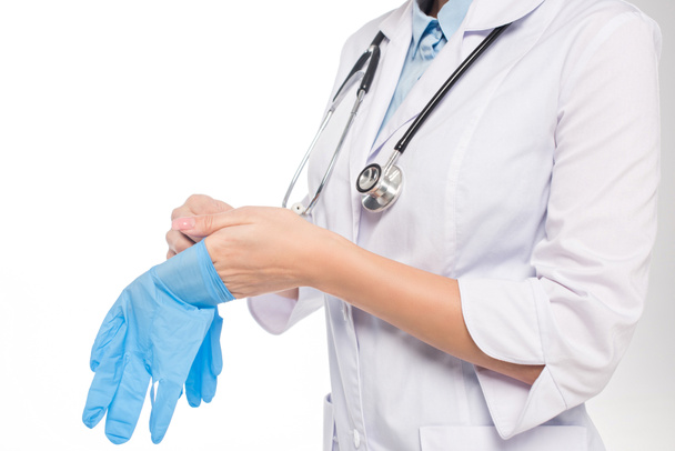 白い上に隔離されたラテックス手袋を身に着けている医師の作物ビュー - 写真・画像