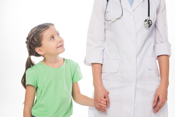 Smiling child holding hands with female pediatrician isolated on white - Fotó, kép